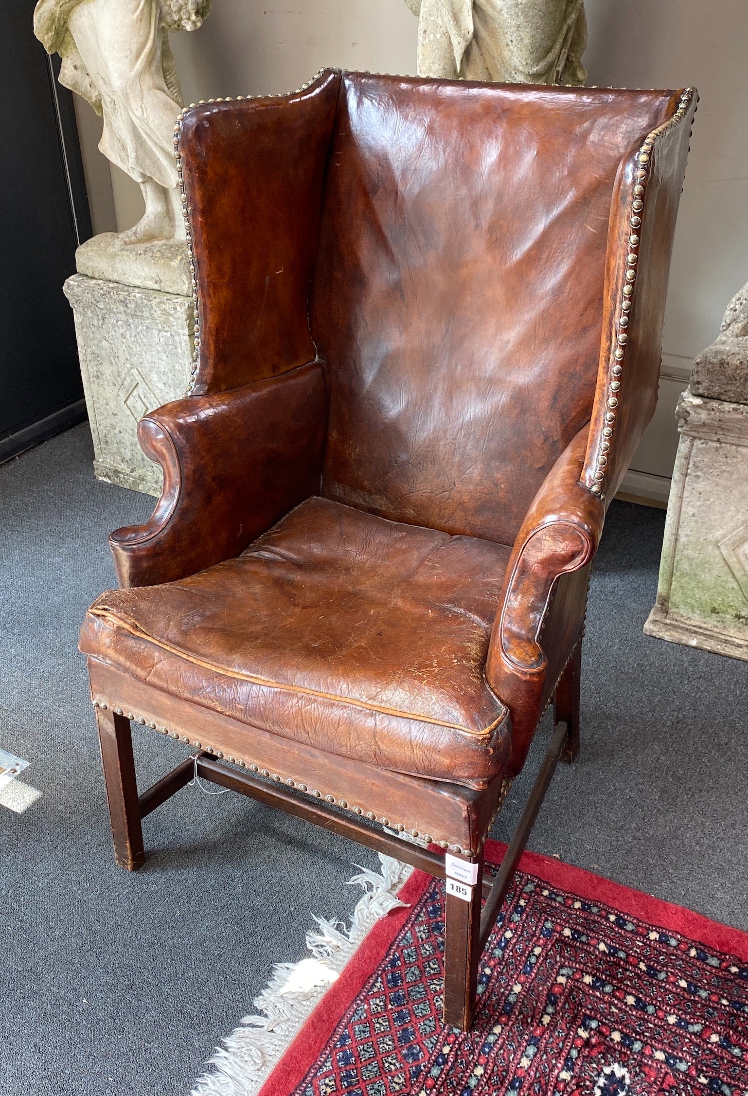 A George III style mahogany brown leather upholstered wing armchair, width 64cm, depth 60cm, height 101cm